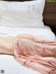 A woman laying on a bed in a pink lingerie.