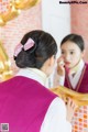 A woman in a pink vest is looking at herself in the mirror.