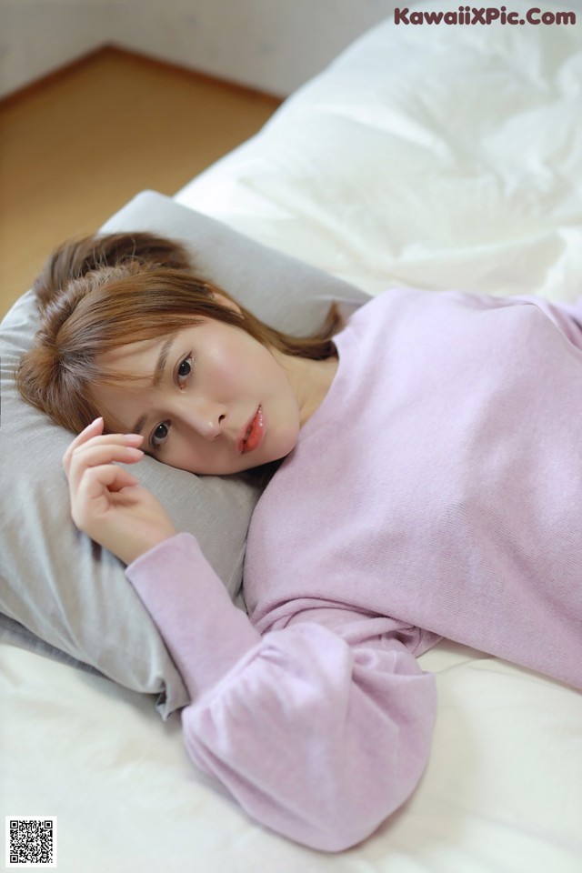 A woman laying on a bed with a pillow.