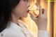 A woman in a white shirt drinking from a glass.