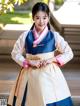 A woman in a blue and white hanbok is posing for a picture.