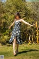 A woman in a blue dress is standing in the grass.