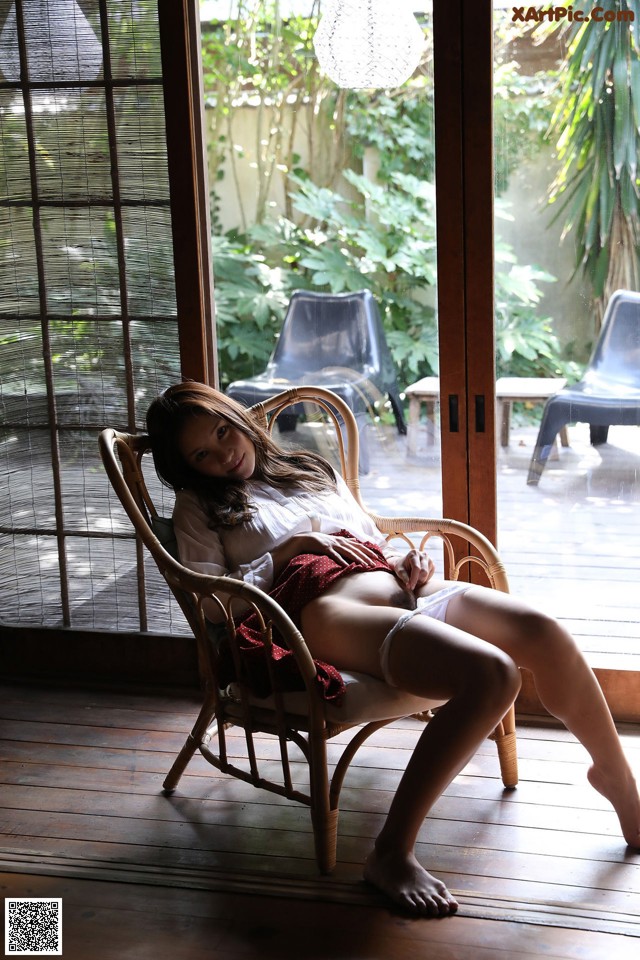 A woman sitting in a chair in front of a window.