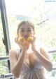 A woman holding two lemons in front of her face.