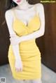 A woman in a yellow dress posing for a picture.