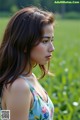 A woman in a floral dress standing in a field.