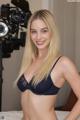 A woman in a black bra posing in front of a camera.