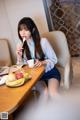 A woman sitting at a table eating a bowl of fruit.