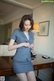 A woman in a gray suit standing next to a desk.