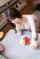 A woman sitting at a table with a plate of fruit.