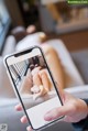 A person taking a picture of a woman laying on a couch.