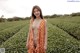 A woman in an orange polka dot dress standing in a field.