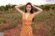 A woman in an orange polka dot dress standing in a field.