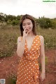 A woman in a polka dot dress standing in a field.