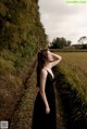 A woman in a black dress standing in a field.