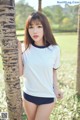 A young woman leaning against a palm tree in a park.