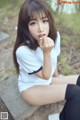 A young woman sitting on a concrete bench eating a piece of food.