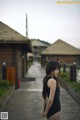 A woman in a black bathing suit standing on a wooden walkway.