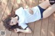 A woman laying on a wooden deck wearing a white shirt and black shorts.