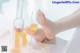 A woman's feet with a glass of champagne next to a bottle of champagne.