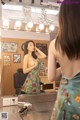 A woman standing in front of a mirror in a salon.