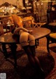 A woman in stockings and stockings sitting at a table.