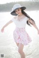 A woman in a white top and pink skirt on the beach.